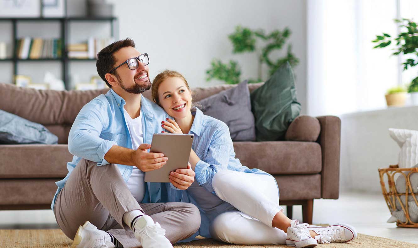 Couple sitting on floor looking at an iPad.