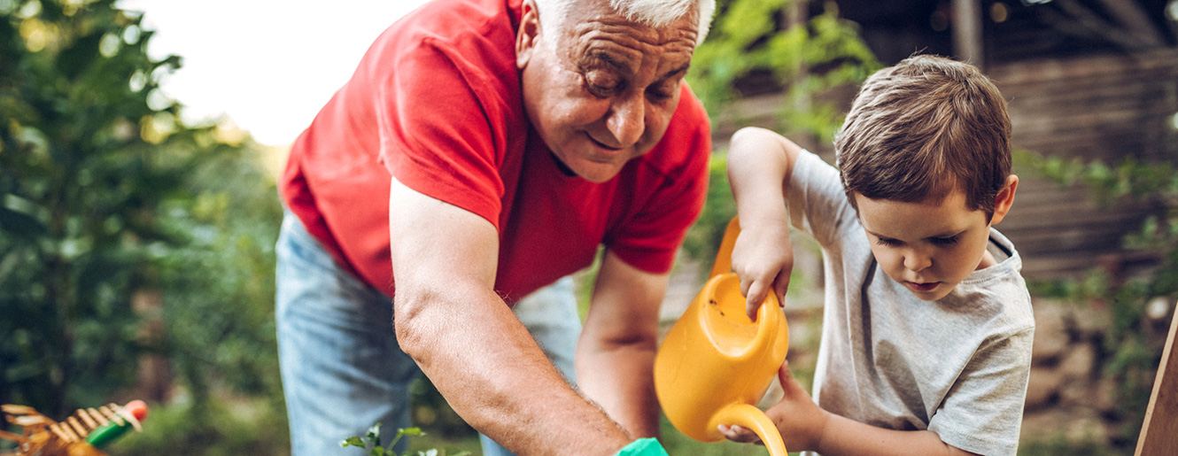 Grandfather with grandson watering plants