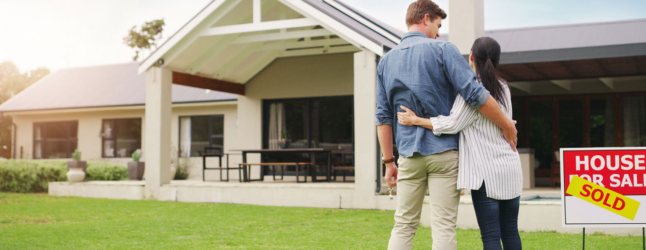 Young couple standing in yard in front of house