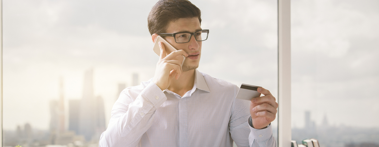 Man at desk holding up a debit card.