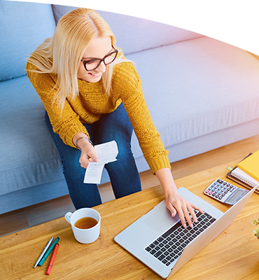 A lady using a laptop computer and looking at receipts